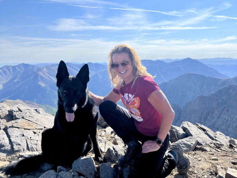 Sonja Stilp MD is pictured with her black dog on a mountain top in the summer months